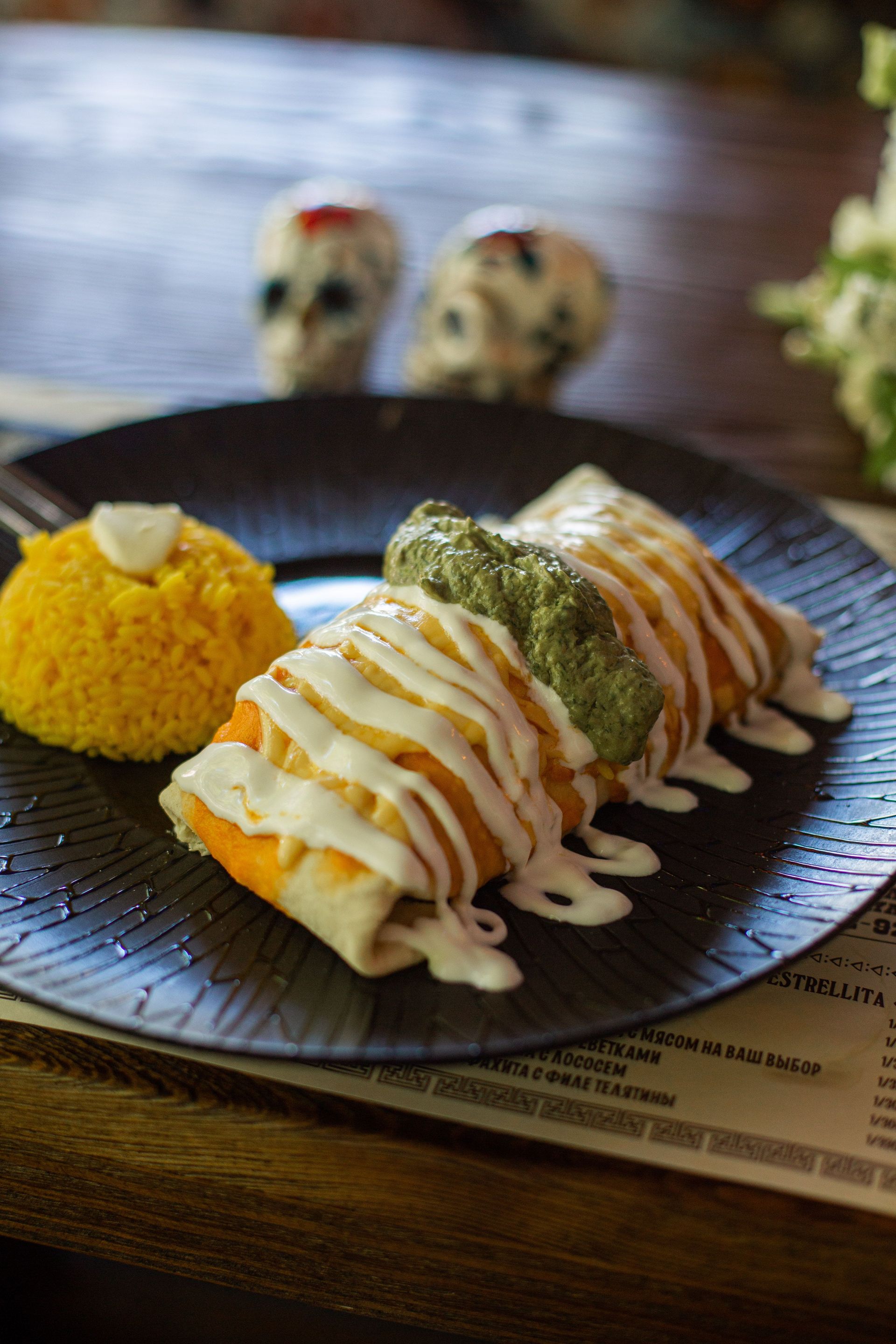 From above of appetizing chimichanga with cheese and guacamole sauces served on plate with saffron rice in Mexican restaurant
