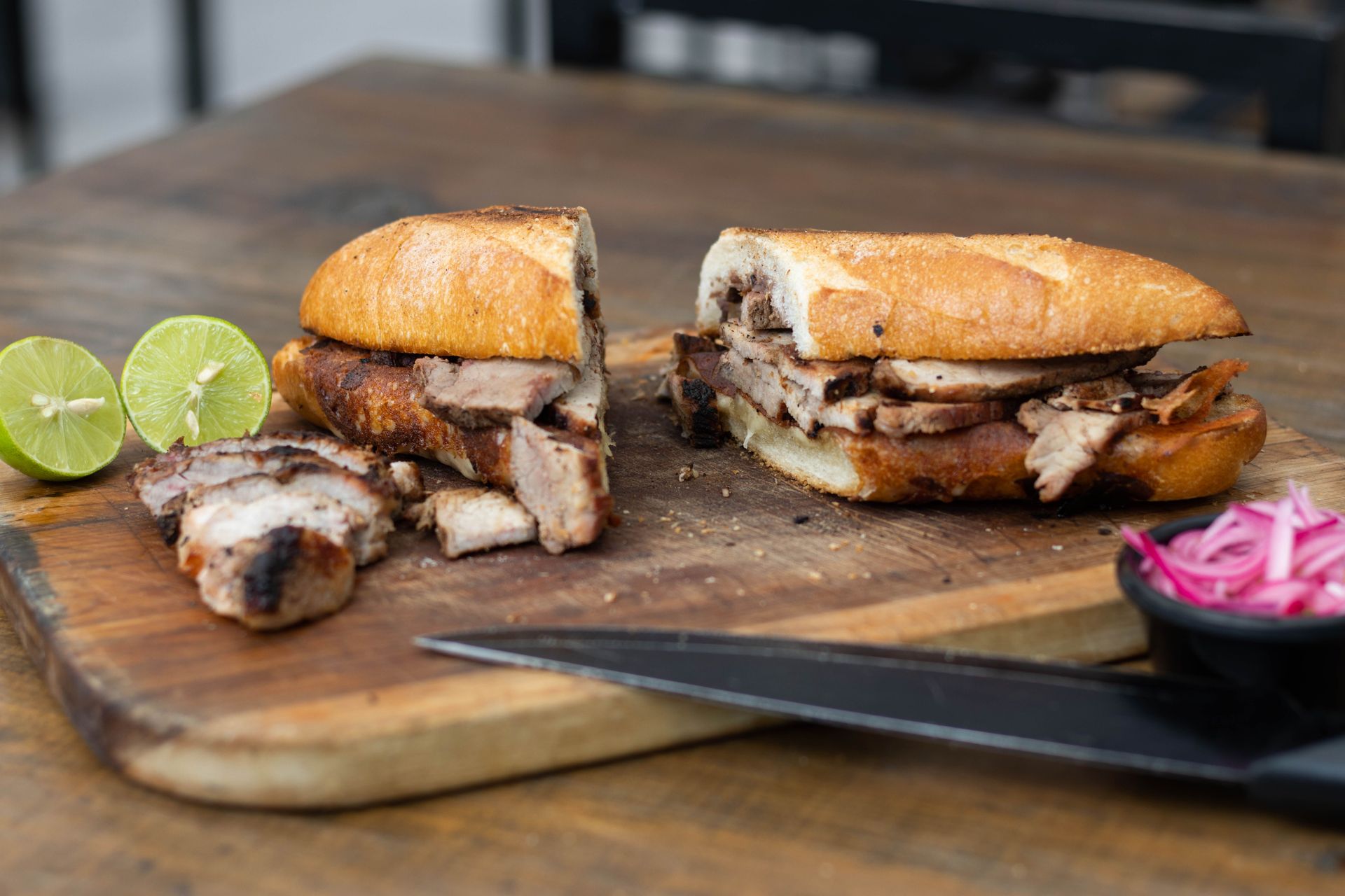 Tasty pork sandwich with sliced lime on a wooden board, perfect for lunch.