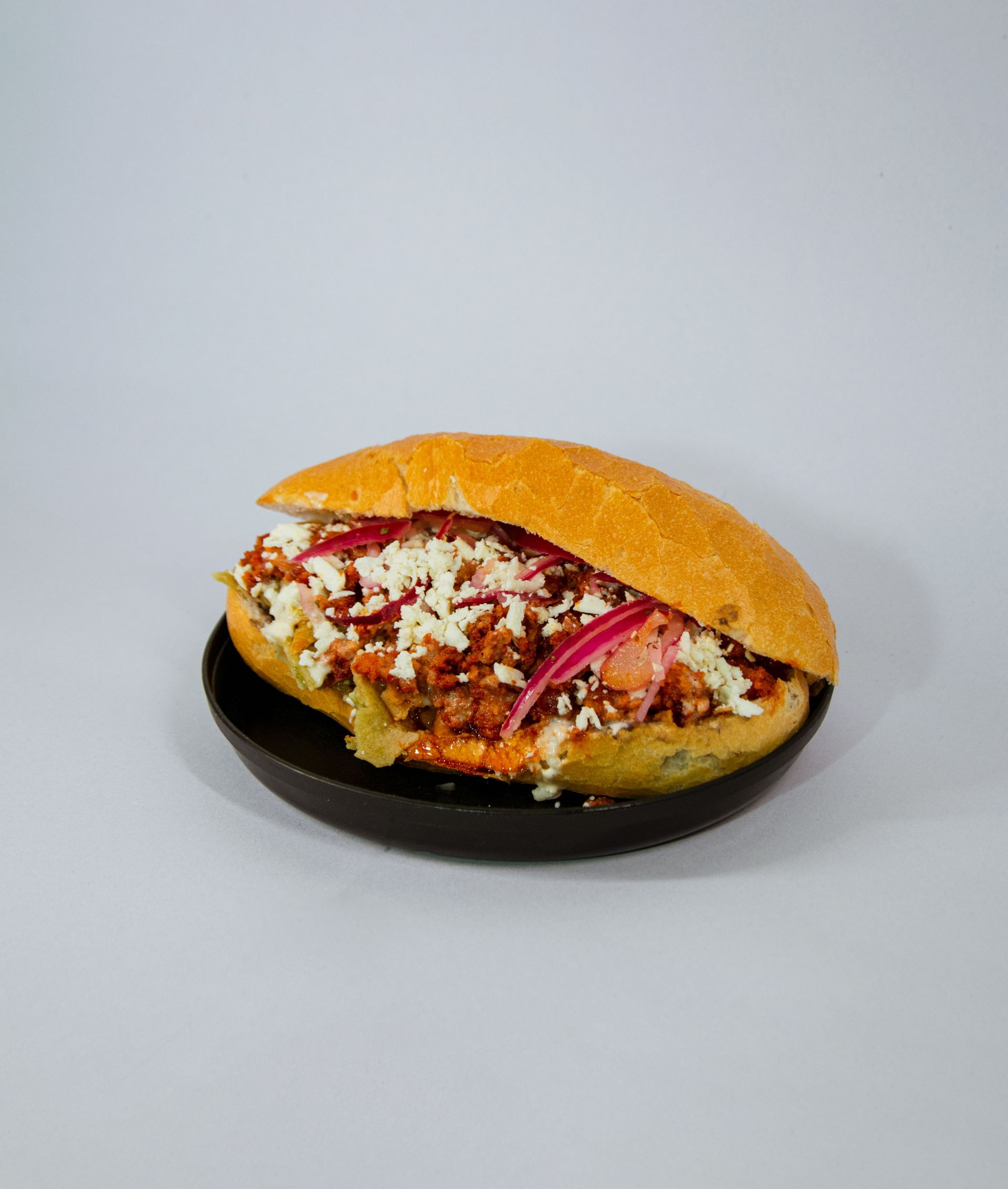 Close-up of a tasty Mexican torta filled with flavorful ingredients on a black plate.